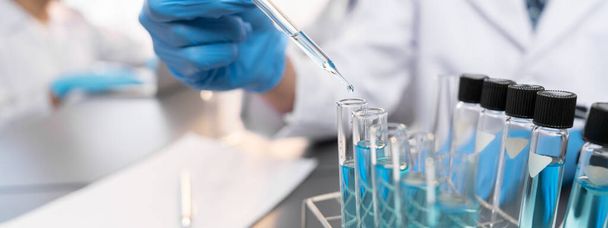 Grupa dedykowanych naukowców przeprowadzić eksperyment chemiczny w laboratorium medycznym, ostrożnie wrzucić dokładną ilość płynu z pipety do probówki na lek szczepionkowy lub rozwój antybiotyków. Neoterynowy - Zdjęcie, obraz