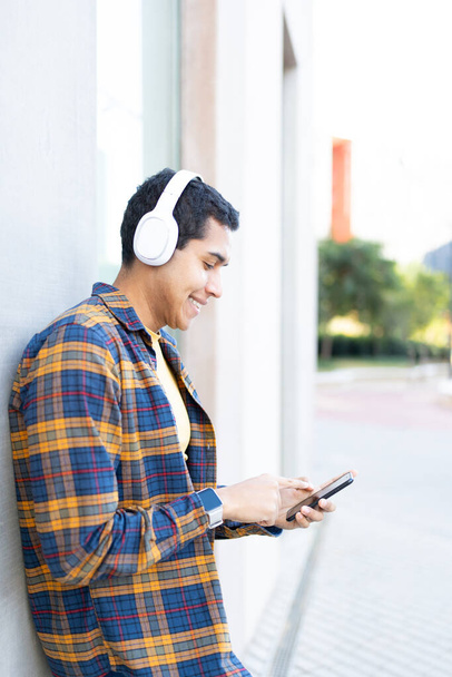 Vertikální fotografie studenta, který používá telefon a poslouchá hudbu - Fotografie, Obrázek