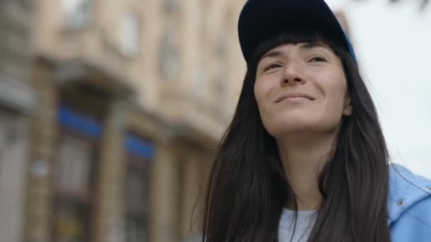 Молода, приваблива жінка-туристка посміхається під час прогулянки в центрі міста, милуючись архітектурою та досліджуючи нові пам'ятки з радістю. концепція подорожуючих людей - Кадри, відео