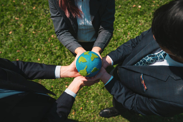 Group of business people hold planet Earth globe together as Earth day concept. Mission to save Earth by business commitment to environment friendly methods and sustainable practices. Gyre - Photo, Image