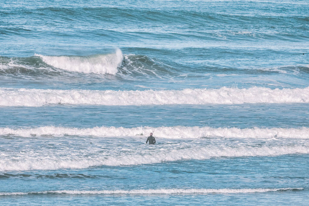São Francisco, Califórnia, EUA - 21 de outubro de 2021. Um surfista entra na água na margem de uma praia da cidade. Conceito, estilo de vida ativo, turismo de viagens - Foto, Imagem