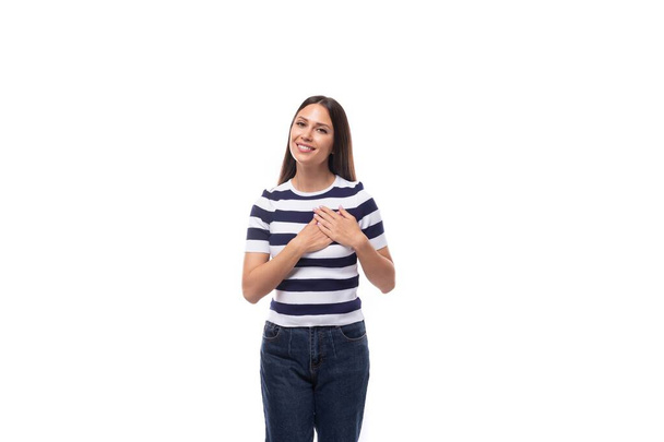eine junge freundliche brünette kaukasische Frau mit leichtem Make-up in gestreiftem T-Shirt und Jeans überzeugt mit einem Lächeln. - Foto, Bild