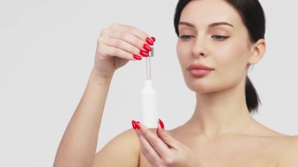 Close-up mooie vrouw met perfecte natuurlijke huid reclame mockup tube gezicht serum voor huidverzorging product. Reclame voor gezichtsserum.  - Video
