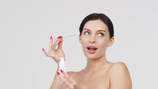 Close-up mooie vrouw met perfecte natuurlijke huid reclame mockup tube gezicht serum voor huidverzorging product. Reclame voor gezichtsserum.  - Video