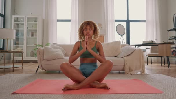 meditazione durante la pratica di yoga femminile snella seduta a gambe incrociate yoga a casa - Filmati, video