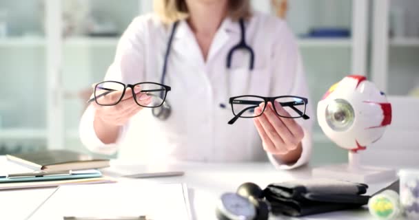 Oftalmólogo muestra modelo de gafas para visión. Miopía y miopía astigmatismo - Metraje, vídeo