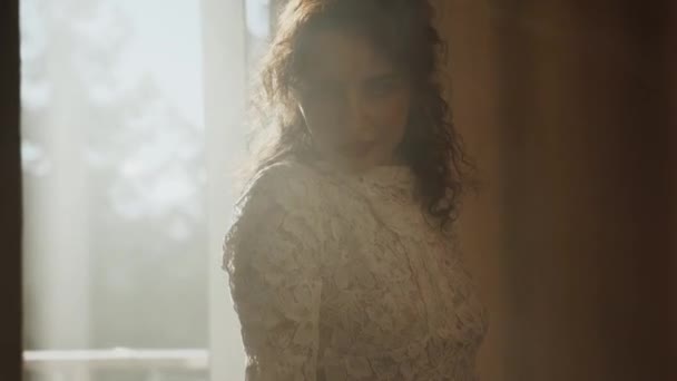 Um modelo de moda em um vestido de noiva posa em uma sala com fumaça e luz solar. Conceito para fotografia de casamento de moda - Filmagem, Vídeo