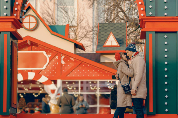 Dans un cadre de vacances, un couple partage un moment tendre, se connectant profondément au charme animé d'un marché de Noël - Photo, image