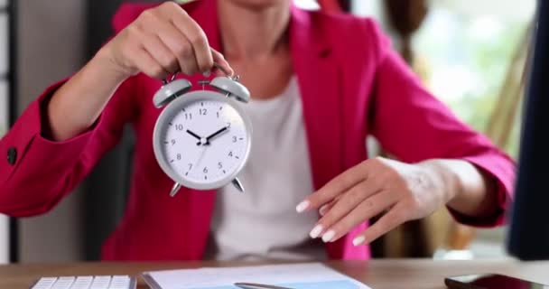 Geschäftsfrau zeigt auf Wecker für zehn Uhr am Arbeitsplatz. Planung der Arbeitsagenda Zeitmanagement und Überstunden Arbeit und Termin - Filmmaterial, Video