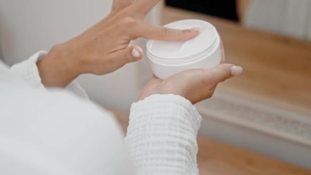 Badkamer elegantie: Een vrouw handen, in close-up, gebruik anti-aging crème uit een pot voor haar huidbehandeling routine.  - Video
