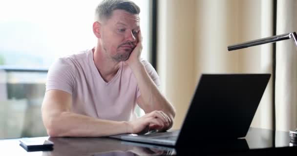 Boring man and stupid work man looks at laptop. Silly business tasks freelancer looking at laptop with dumb emotions sitting at table - Filmmaterial, Video