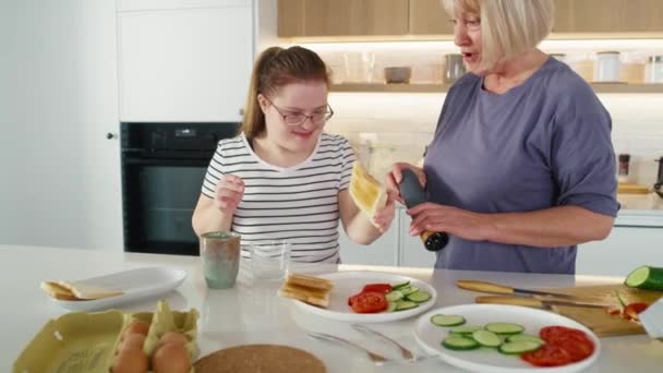 Žena s Downovým syndromem a její matka podávají snídani. Snímek s RED heliovou kamerou v 8K.  - Záběry, video