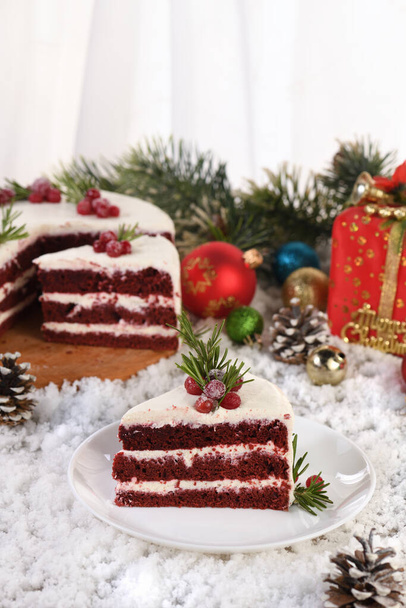 赤いベルベットケーキは白いバタークリームをトッピングした伝統的な赤いチョコレートケーキで、砂糖漬けのクランベリーとローズマリーのクリスマスリースで飾られています。. - 写真・画像
