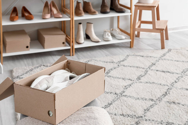 Bench with cardboard box and stylish female sneakers in boutique - Photo, Image