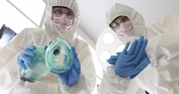 Dos médicos con trajes y máscaras protectoras sostienen la máscara de oxígeno y planean recibir masajes cardíacos. Concepto de primeros auxilios - Metraje, vídeo