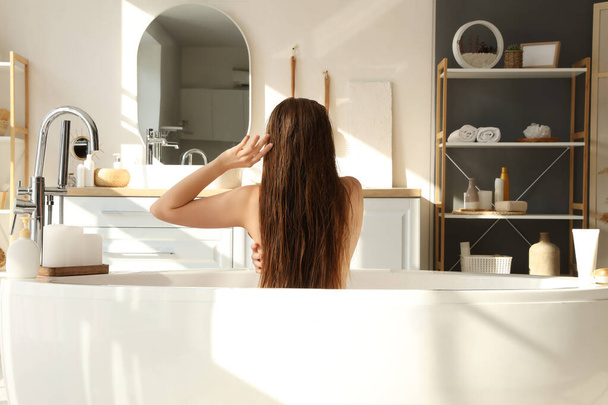 Mujer joven tomando baño en casa, vista trasera - Foto, imagen