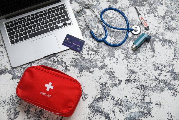 Laptop, creditcard en EHBO kit op grijze achtergrond - Foto, afbeelding