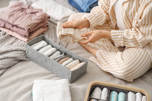 Woman sorting clothes on bed in bedroom, closeup - Photo, Image