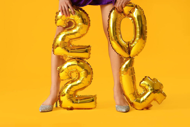 fiatal nő magassarkúban szám 2024 sárga alapon - Fotó, kép