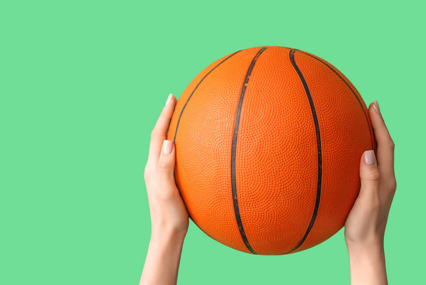 Mãos femininas com bola para jogar basquete no fundo verde - Foto, Imagem