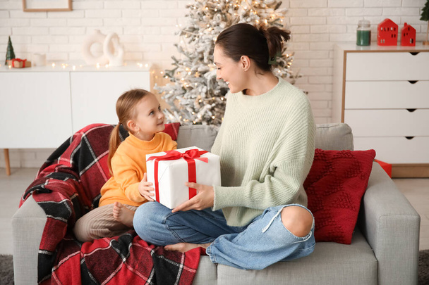 若い母親は自宅で彼女の小さな娘クリスマスプレゼントを与える - 写真・画像