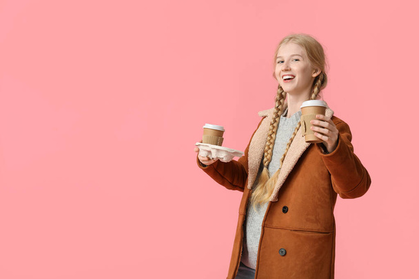 Schöne junge glückliche Frau mit Pappbechern Tee auf rosa Hintergrund - Foto, Bild