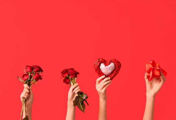 色の背景にハート,赤いバラ,ギフトボックスが付いている女性の手. バレンタインデーのお祝い - 写真・画像