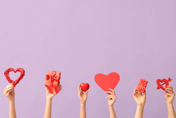 Γυναικεία χέρια με διαφορετικές καρδιές και κουτιά δώρων σε λιλά φόντο. Γιορτή του Αγίου Βαλεντίνου - Φωτογραφία, εικόνα