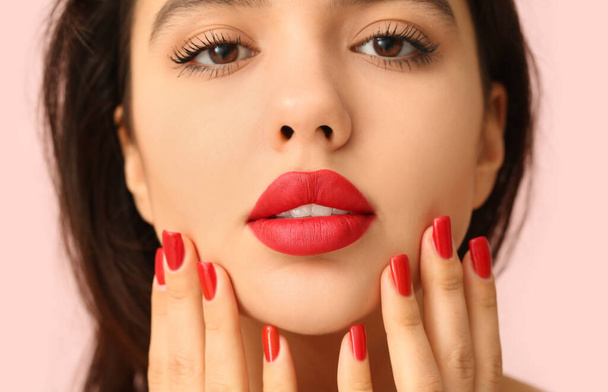 Kaunis nuori nainen punaisella huulipunalla vaaleanpunaista taustaa vasten, lähikuva - Valokuva, kuva