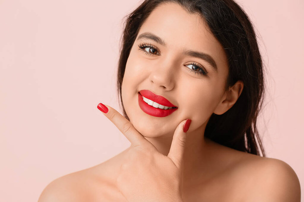 Hymyilevä nuori nainen punaisella huulipunalla vaaleanpunaista taustaa vasten, lähikuva - Valokuva, kuva