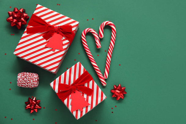 Composition with beautiful Christmas gifts, candy canes and decor on green background - Photo, Image