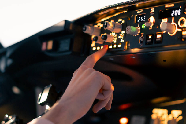 mão de close-up do piloto capitão pressiona os botões no painel de controle para ligar o motor do avião simulador de voo close-up - Foto, Imagem