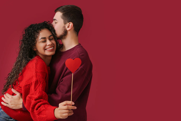 Jeune couple avec coeur en papier pour la Saint-Valentin sur fond rouge - Photo, image