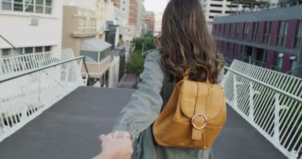 Back, travel and smile with a woman leading you on a bridge in the city for love or romance for dating. Portrait, holding hands and walking with a happy young couple in an urban town for tourism. - Footage, Video