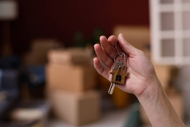 Primo piano di donna ottenere nuova chiave dal nuovo appartamento, lei in piedi nella stanza con contenitori - Foto, immagini