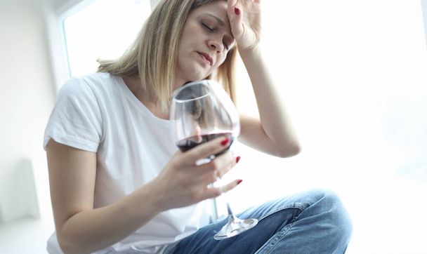 Mujer cansada con un vaso de vino tinto sosteniendo su cabeza. Concepto de problemas psicológicos - Foto, Imagen