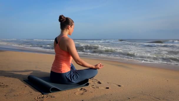Frau beim Yoga - meditieren und entspannen in Padmasana Lotus Asana Pose mit Kinnmudra im Freien am tropischen Strand bei Sonnenuntergang - Filmmaterial, Video