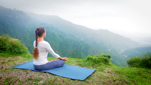 Žena dělá jógu - meditace v Padmasana (Lotus Pose) venku v horách při západu slunce - Záběry, video