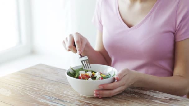 close up of young woman eating salad at home - Materiaali, video