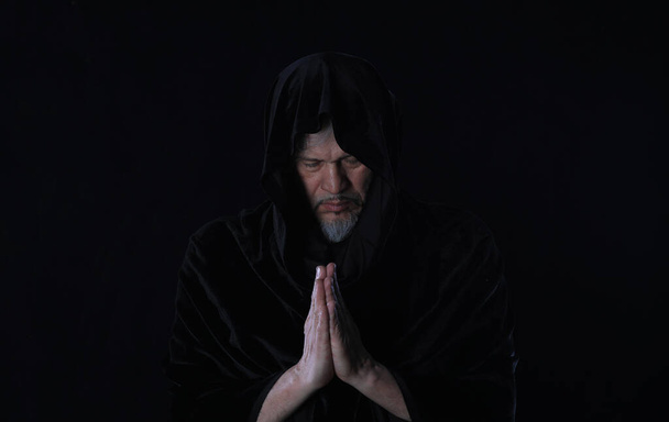 Porträt eines mittelalterlichen Mönchs mit Kapuze auf schwarzem Hintergrund - Foto, Bild