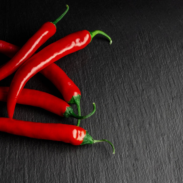 Groenten. Kruiden. Een kruidige rode Mexicaanse chili peper ligt op een zwarte steen - Foto, afbeelding