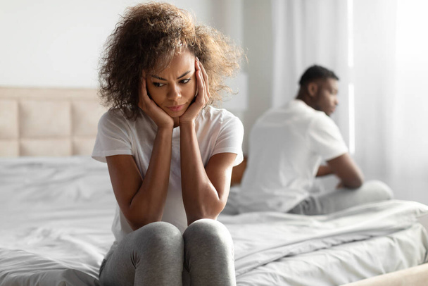 Evlilik Krizi. Yatağın farklı taraflarında oturan mutsuz siyahi çift, yatak odasının iç kısmında tartıştıktan sonra somurtuyor, kayıtsızlık, anlaşmazlık ve ilişki sorunları yaşıyor. - Fotoğraf, Görsel