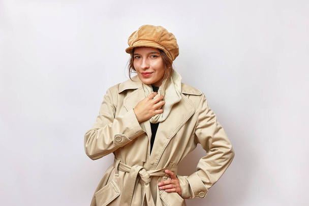 Una hermosa chica está vestida con un impermeable de otoño beige y un sombrero marrón cálido.. - Foto, Imagen