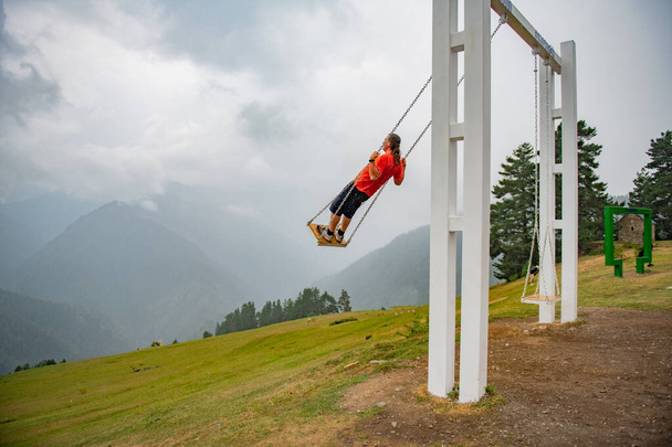 Gravity-Defying Joy: Man op Swing in oranje T-shirt. Hoge kwaliteit foto - Foto, afbeelding