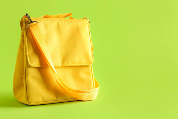 Жовта обідня сумка на зеленому фоні - Фото, зображення