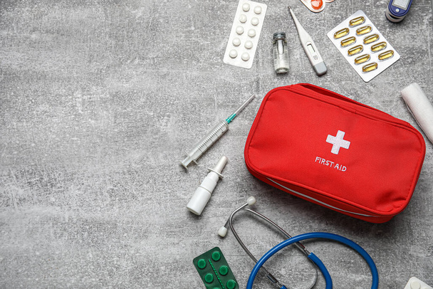 Kit di pronto soccorso e pillole su sfondo grigio grunge - Foto, immagini