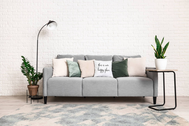 Interiér moderního obývacího pokoje s šedou pohovkou, standardní lampou a pokojovými rostlinami - Fotografie, Obrázek