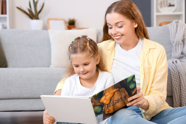 Kleines Mädchen mit ihrer Mutter, die zu Hause Buch liest - Foto, Bild