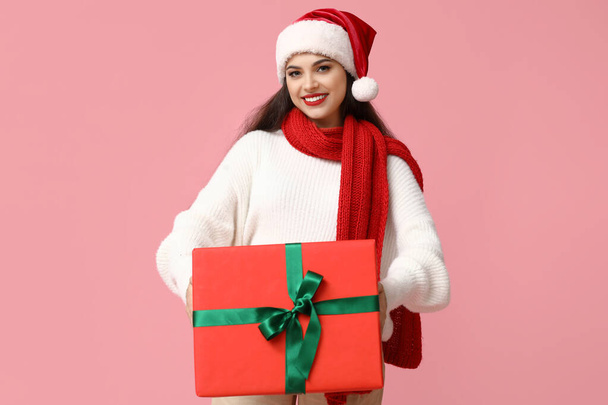 Kaunis nuori nainen Santa hattu joululahja vaaleanpunainen tausta - Valokuva, kuva