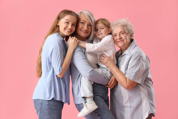 Маленька дівчинка з сім'єю обіймається на рожевому фоні - Фото, зображення